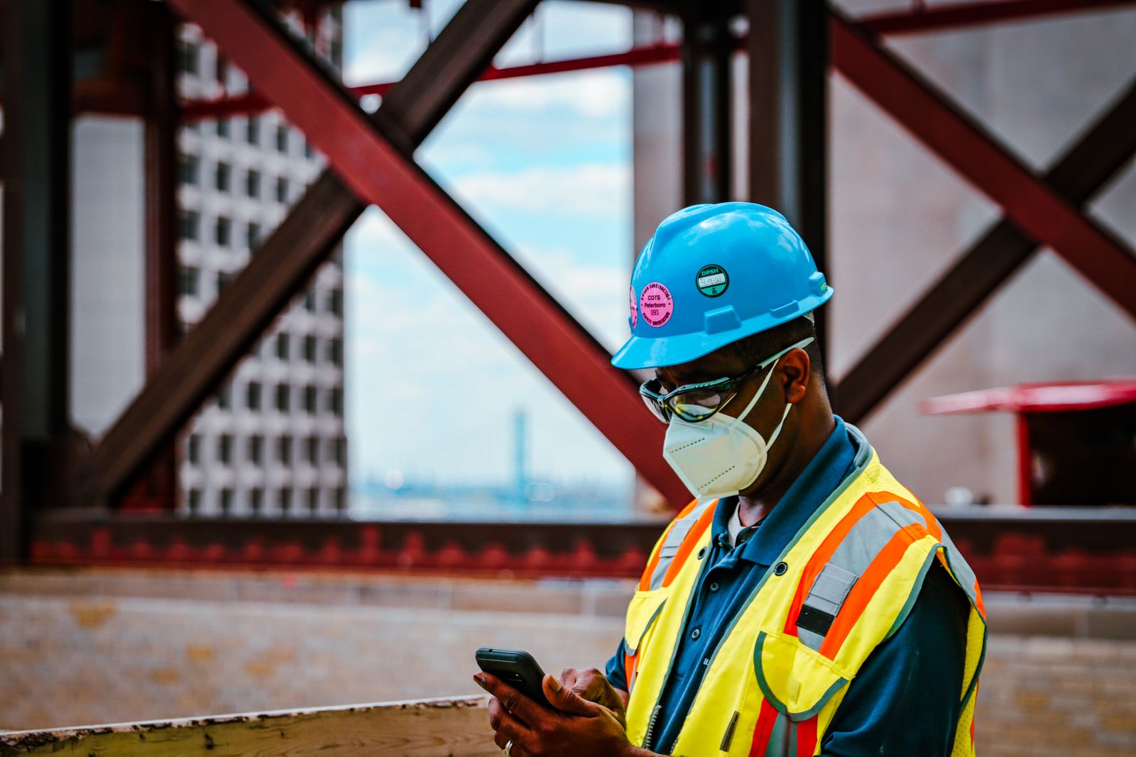 Tradesman in safety gear looking at his phone on site
