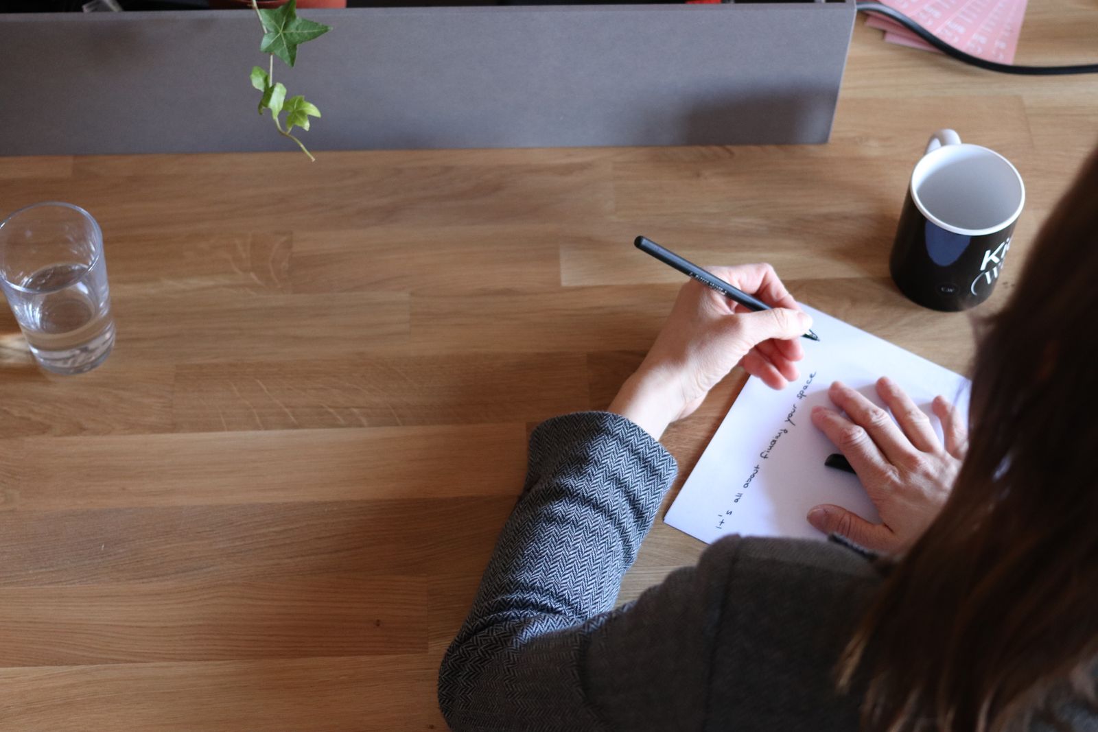 Marketer taking notes at a wooden desk while planning a page