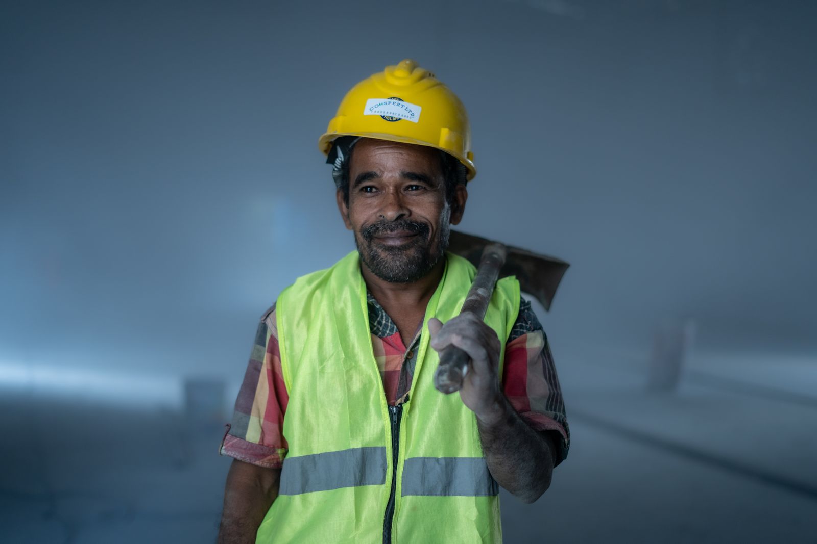 Smiling tradesman in safety gear holding a tool