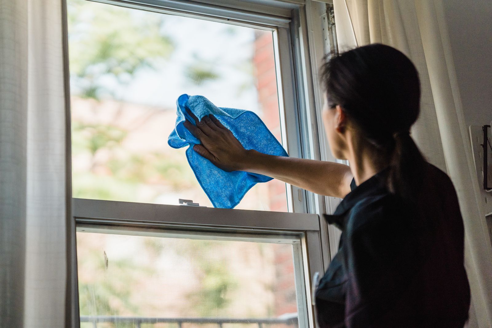 Cleaner polishing a window with a microfibre cloth
